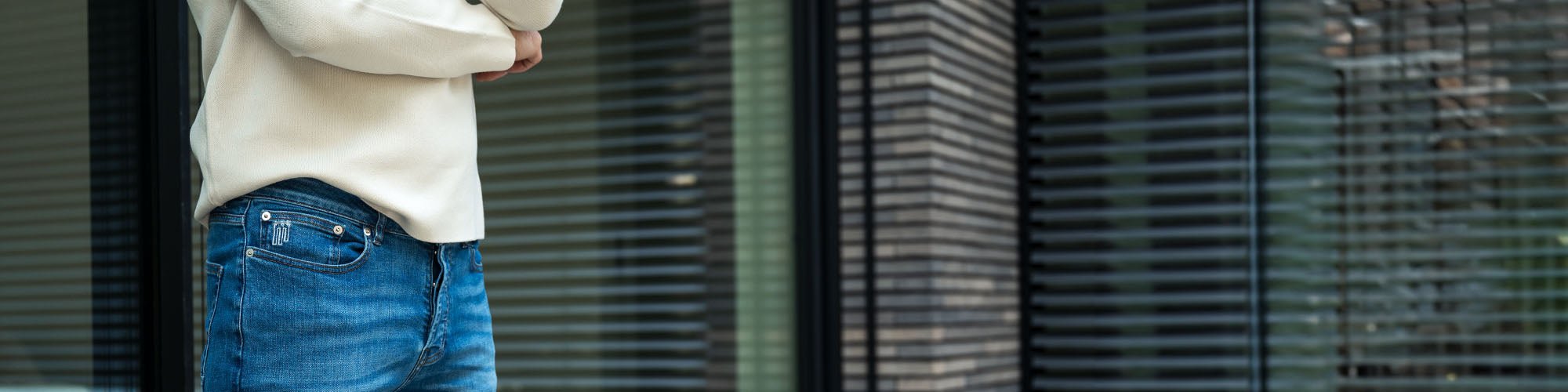 Man in donkerblauwe spijkerbroek en zandkleurige sweater