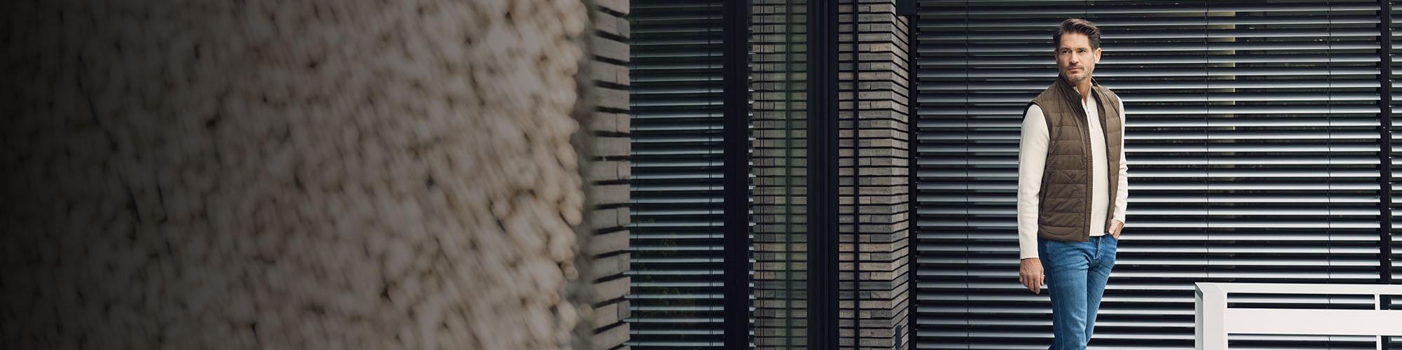 Man in blauwe jeans, witte sweater en groene bodywarmer