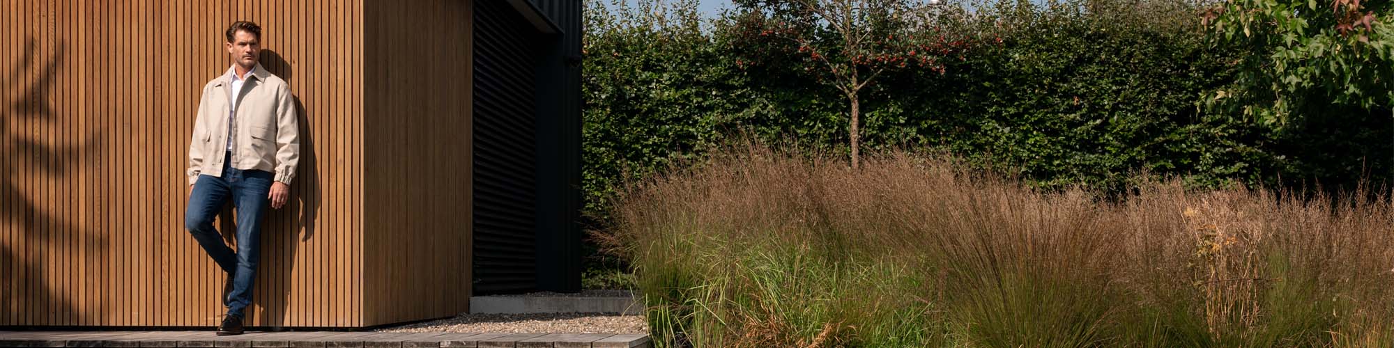 Man in donkerblauwe jeans tegen wand 