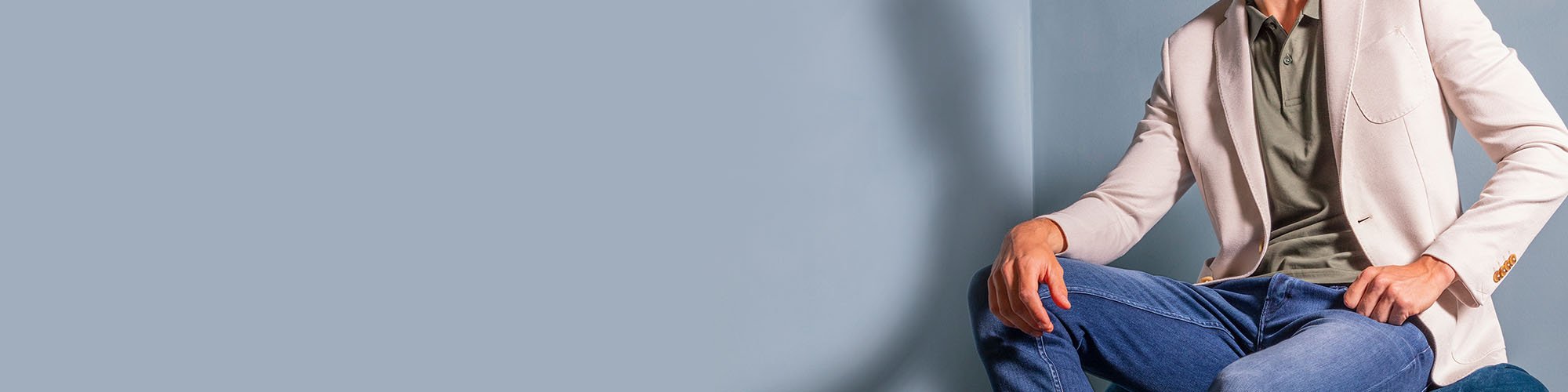 Man in witte colbert en donkerblauwe spijkerbroek