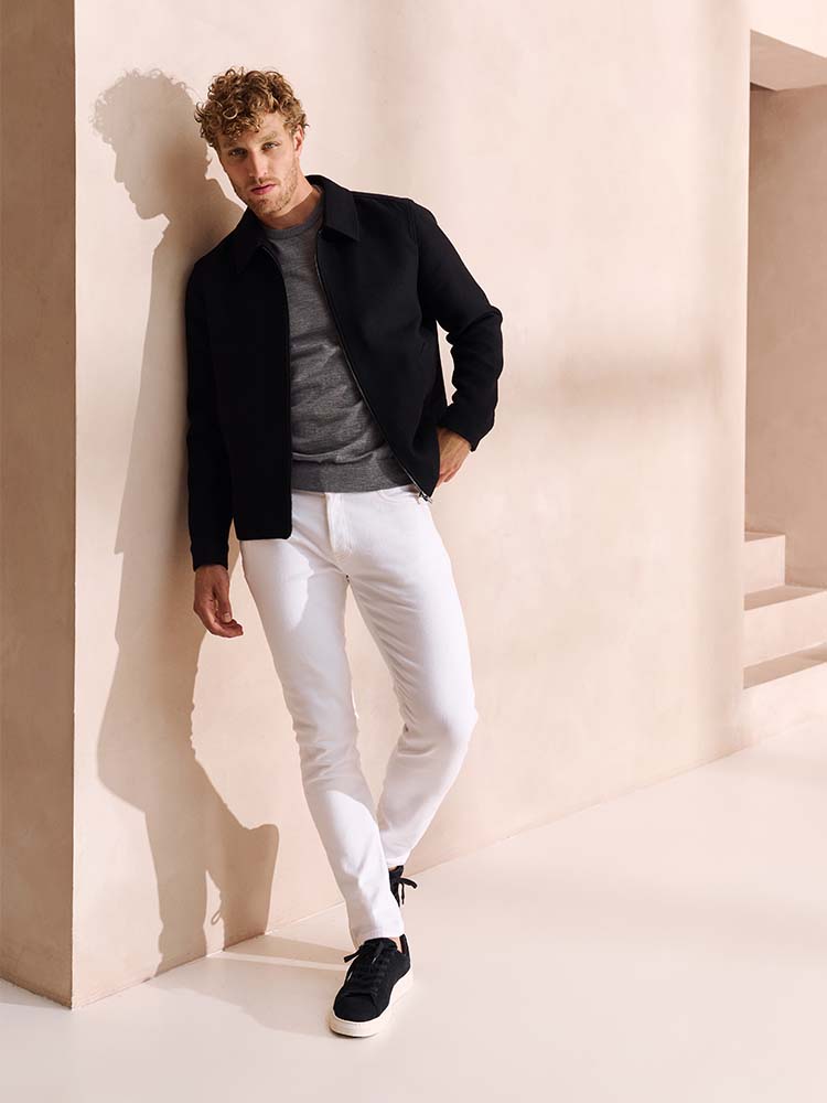 Man in witte Bukser jeans, grijze trui en donkerblauw jack