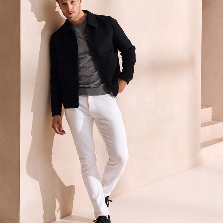 Man in witte Bukser jeans, grijze trui en donkerblauw jack