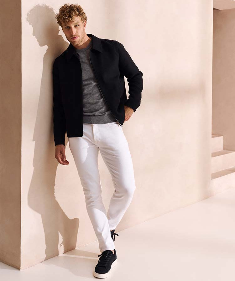 Man in witte Bukser jeans, grijze trui en donkerblauw jack