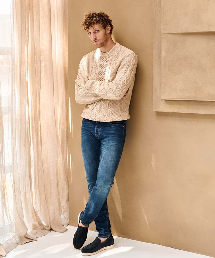 Man in blauwe Bukser jeans en beige wollen trui
