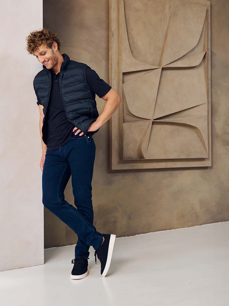 Man in donkerblauwe Bukser jeans, donkerblauwe polo en jas