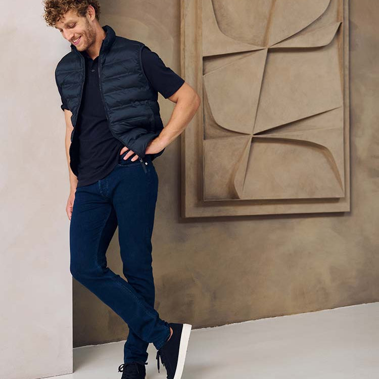 Man in donkerblauwe Bukser jeans, donkerblauwe polo en jas