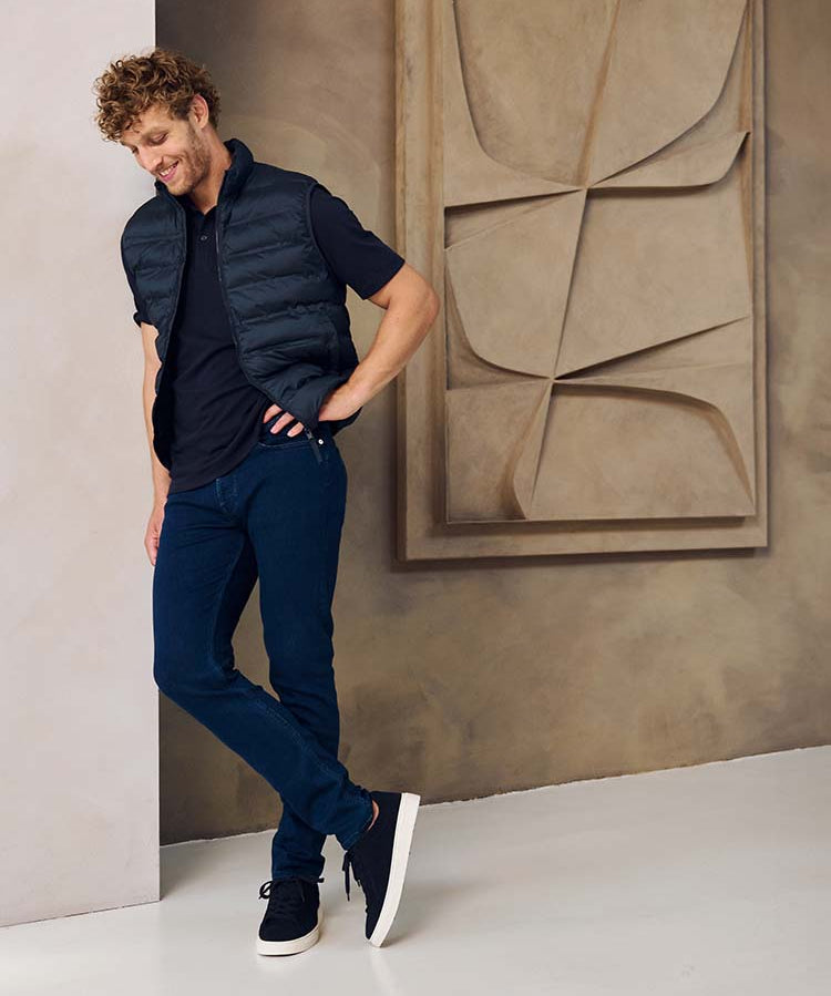 Man in donkerblauwe Bukser jeans, donkerblauwe polo en jas
