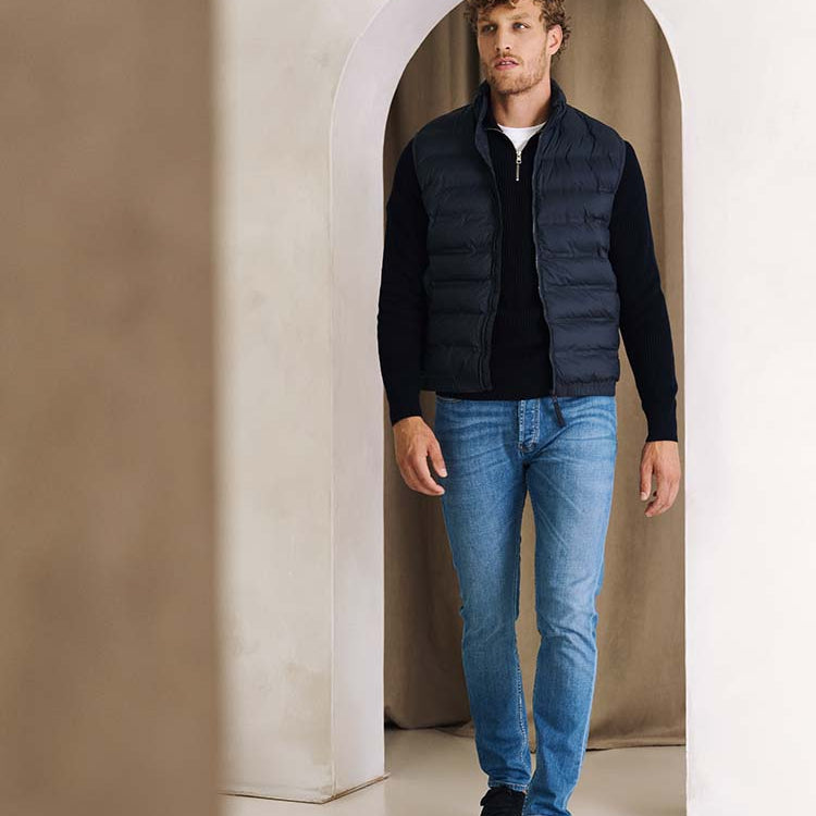 Man in ichtblauwe Bukser jeans, zip trui en bodywarmer