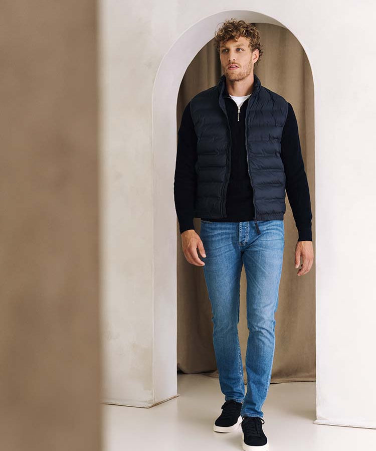 Man in ichtblauwe Bukser jeans, zip trui en bodywarmer