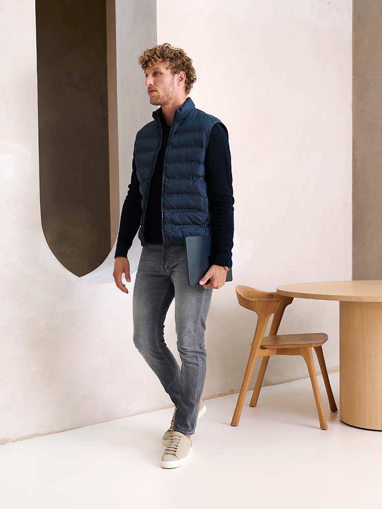 Man in grijze Bukser jeans met donkerblauwe trui en bodwarmer