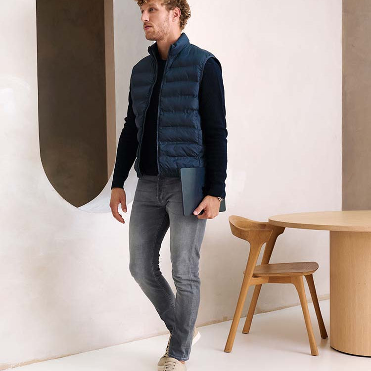 Man in grijze Bukser jeans met donkerblauwe trui en bodwarmer