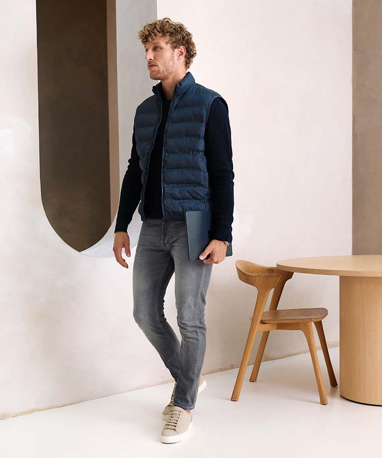 Man in grijze Bukser jeans met donkerblauwe trui en bodwarmer