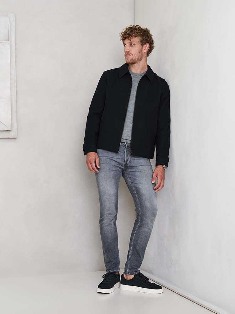 Man in grijze Bukser jeans, grijze trui en blauwe jas