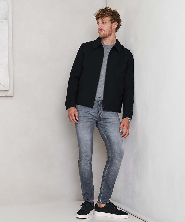 Man in grijze Bukser jeans, grijze trui en blauwe jas