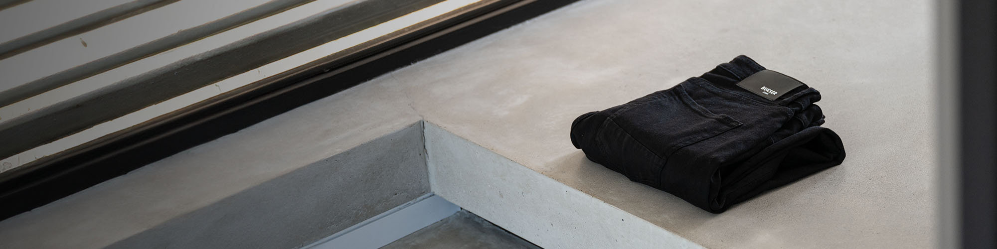 Zwarte Bukser jeans opgevouwen op een betonnen verhoging